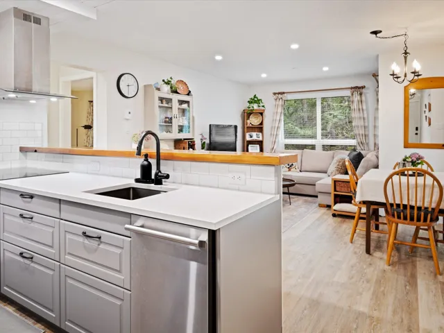 Kitchen with a sink, gray cabinetry, exhaust hood, open floor plan, and recessed lighting