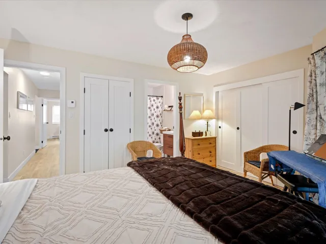 Bedroom with light wood-style flooring, connected bathroom, and baseboards