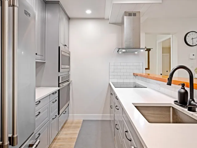 Kitchen featuring stainless steel appliances, a sink, island range hood, tasteful backsplash, and gray cabinetry