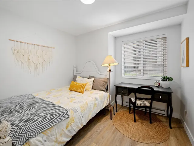 Bedroom with wood finished floors, a desk, baseboards, and baseboard heating