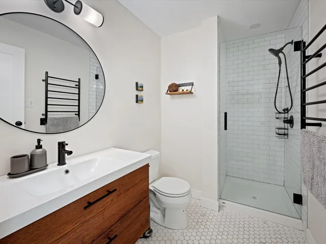 Bathroom with a shower stall, toilet, vanity, baseboards, and tile patterned floors