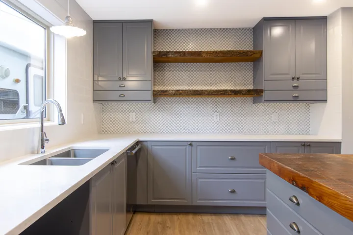 Kitchen with gray cabinets, open shelves, and light wood finished floors