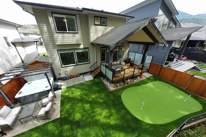 Rear view of property featuring a fenced backyard, a deck with mountain view, a hot tub, an outdoor hangout area, and a patio area