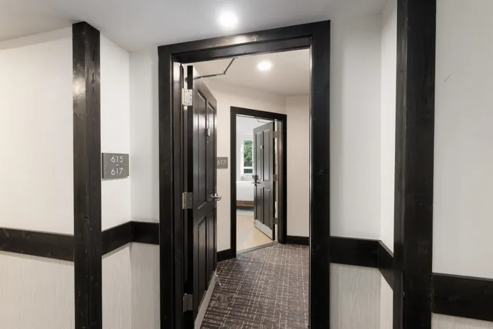Entryway with dark trim framing white walls and wood-finish flooring