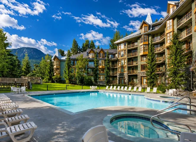 Expansive outdoor pool area featuring a large swimming pool, an integrated hot tub, and surrounding concrete decking