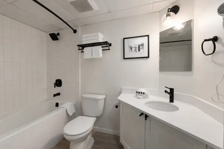 Bathroom featuring a white vanity with an integrated sink, matte black faucet, and a large mirror