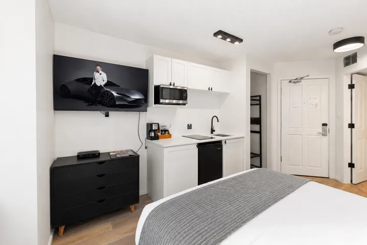 Integrated kitchenette featuring white cabinetry, a microwave, black faucet, and compact refrigerator