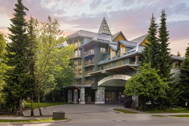 Multi-story commercial building featuring a prominent stone facade, pitched metal roof, and multiple balconies