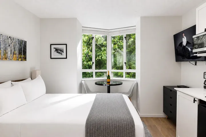 Bright room featuring a prominent bay window, hard surface flooring, and a wall-mounted television