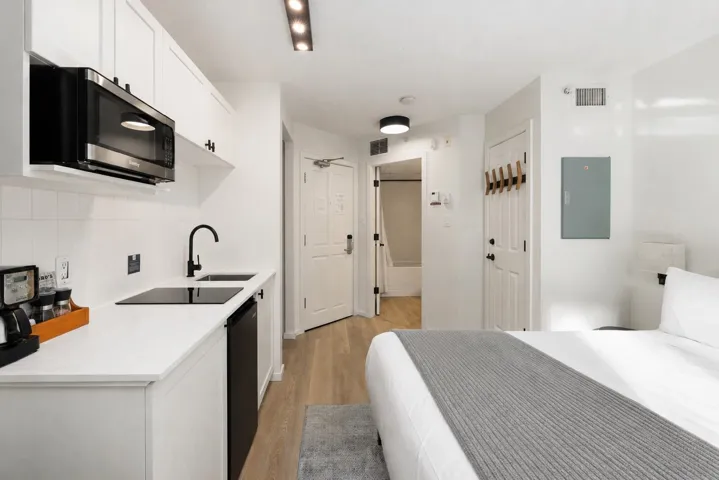 Compact kitchenette featuring white shaker-style cabinetry, quartz-finish countertop, and integrated microwave