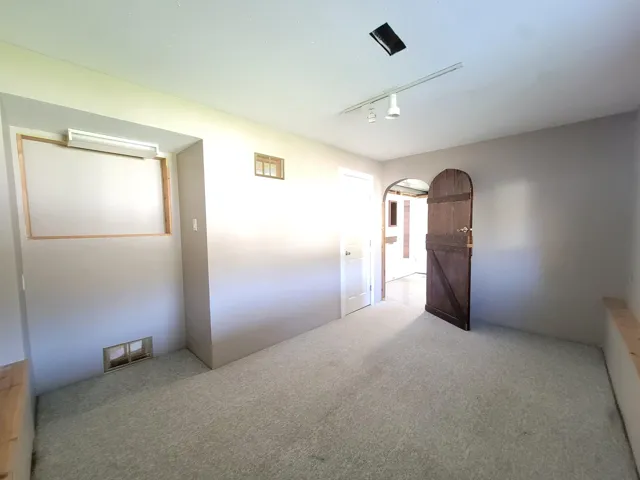 Unfurnished bedroom with track lighting, carpet flooring, and arched walkways