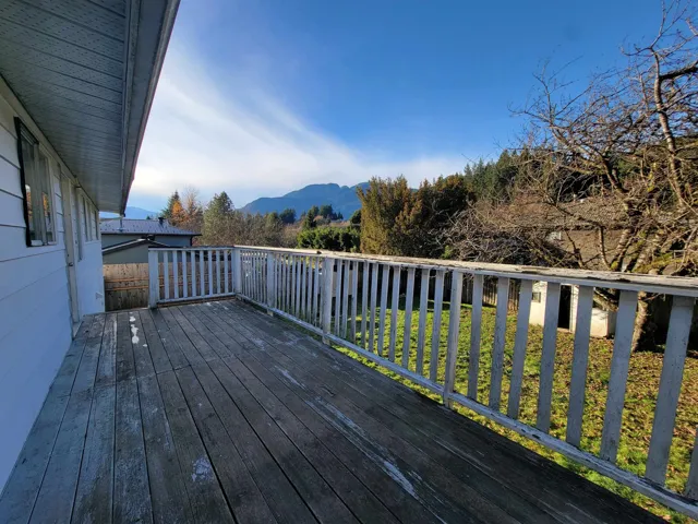 Deck featuring a mountain view, a yard, and view of scattered trees