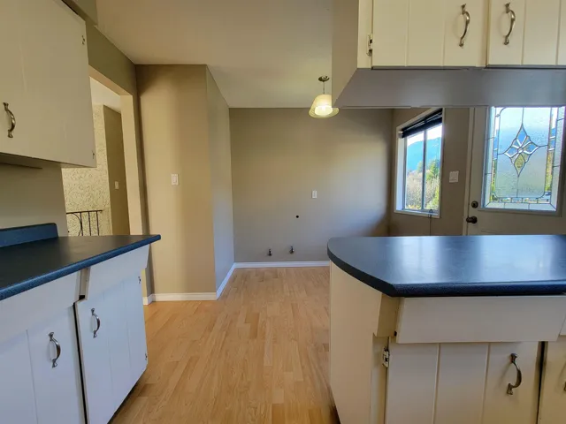 Kitchen featuring light wood-type flooring, pendant lighting, dark countertops, and white cabinets