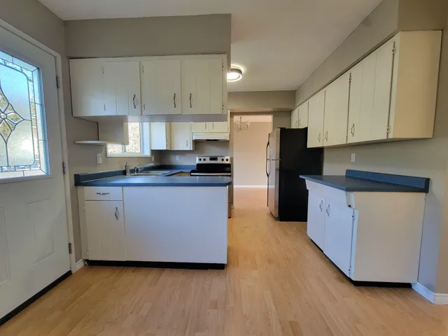 Kitchen with a peninsula, white cabinets, and light wood-style flooring