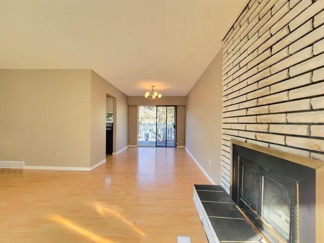 Unfurnished living room featuring a chandelier, light wood-type flooring, and a fireplace