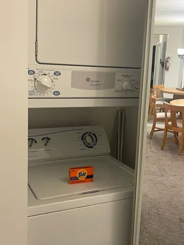 Laundry room with light carpet and stacked washer / drying machine