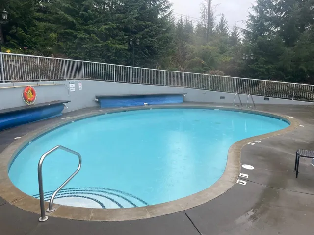 Community pool featuring a wooded view and a patio area