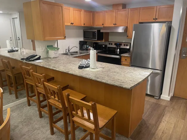 Kitchen with stainless steel appliances, a breakfast bar area, a peninsula, under cabinet range hood, and tasteful backsplash