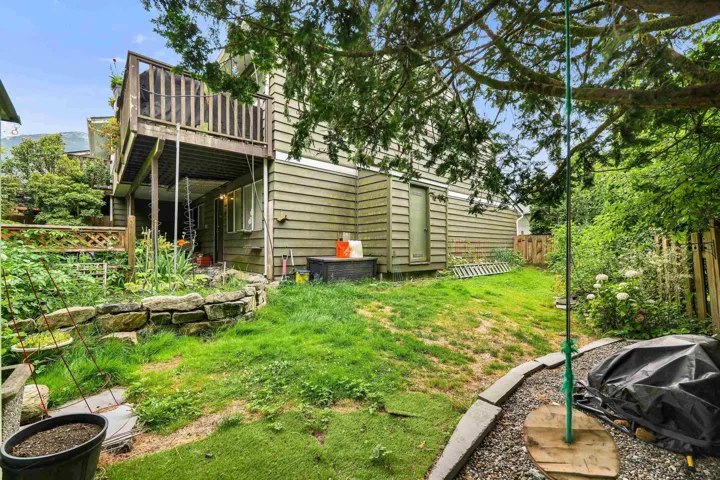 Multi-level outdoor space featuring a second-story wooden deck, a ground-level covered patio, and a sloped grass lawn