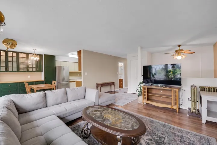 Open-concept living space featuring wood-finish flooring, a ceiling fan, and a built-in radiator