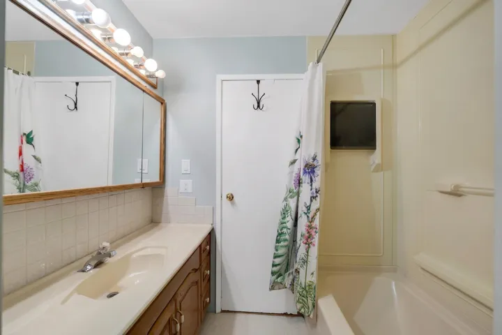 Bathroom featuring a built-in vanity with light wood-finish cabinetry, an integrated sink, and an extended countertop