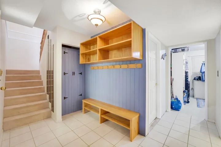 Entryway featuring ceramic tile flooring, built-in wooden shelving, wooden bench seating, and a coat rack with multiple hooks