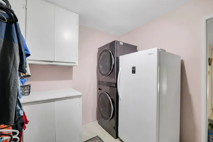 Dedicated laundry area featuring white wall cabinetry, coordinating base cabinetry with a countertop, and light-toned flooring
