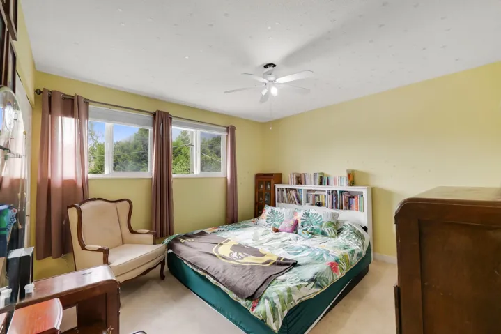 Room featuring light yellow walls, a ceiling fan, and multiple windows
