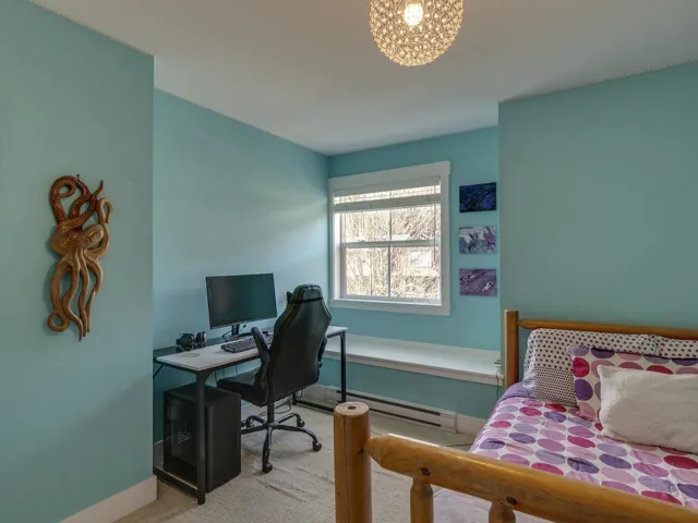 Bedroom with a desk, carpet flooring, and a baseboard heating unit