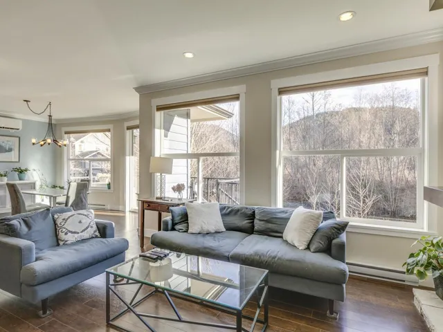 Living area with crown molding, baseboard heating, a chandelier, dark wood-style flooring, and a wall mounted air conditioner