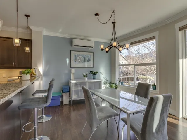 Dining area with dark wood finished floors, ornamental molding, a wall mounted air conditioner, and a chandelier