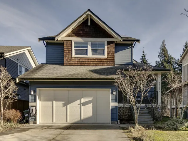 View of front facade featuring a shingled roof, a garage, and driveway