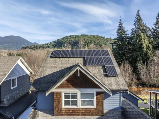 View of front of property featuring solar panels, roof with shingles, and a mountain view
