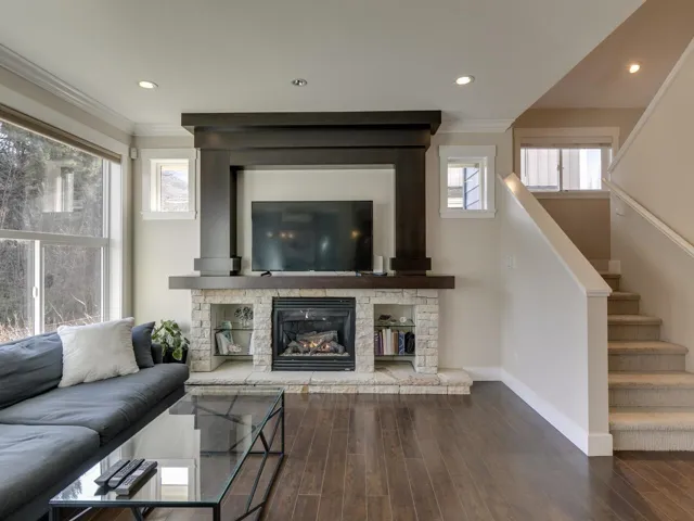 Living room with wood finished floors, stairs, recessed lighting, a stone fireplace, and ornamental molding