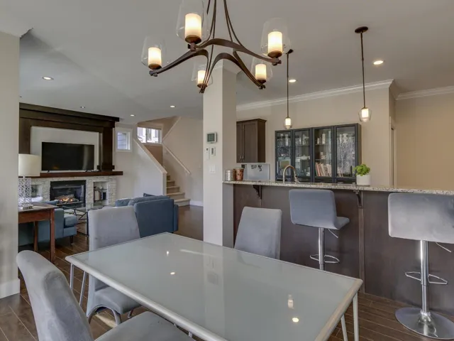 Dining room featuring a stone fireplace, recessed lighting, crown molding, wood tiled floors, and stairs