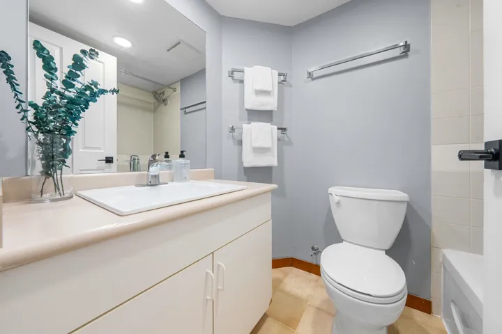 Bathroom featuring a single vanity with an integrated sink, white cabinetry, and a neutral-toned countertop