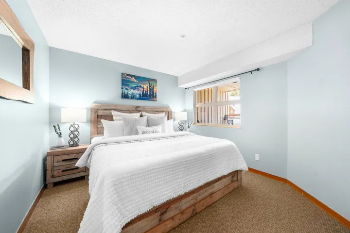 Spacious bedroom featuring light blue walls and a window with a dark curtain rod