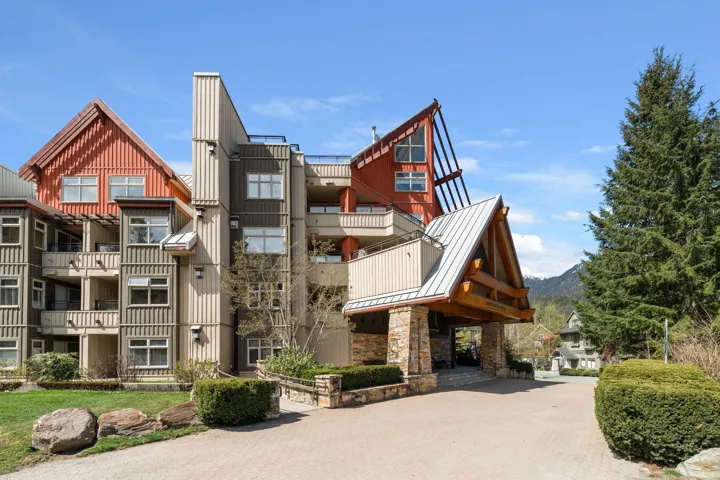 Multi-level building with varied architectural elements, featuring a stone-clad porte-cochère entrance