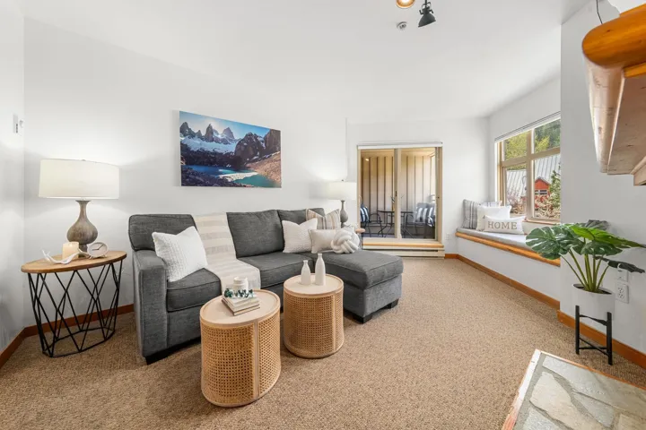 Plush carpeting throughout with a built-in window seat, a sliding glass door to an exterior balcony, and a stone hearth