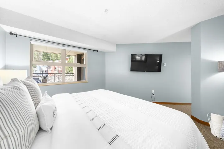 Contemporary bedroom featuring light blue walls and a large window with a roller shade