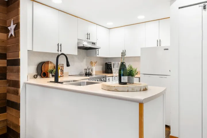 Modern kitchen with white cabinetry, light countertops, and a black gooseneck faucet