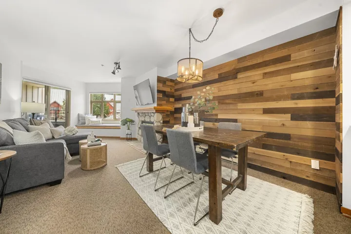 Dining area with a natural wood plank accent wall and a drum pendant light fixture