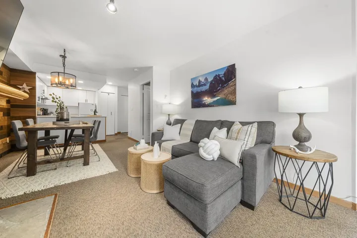 Open-concept living space featuring a carpeted floor, white walls, and a built-in wood-finish accent wall