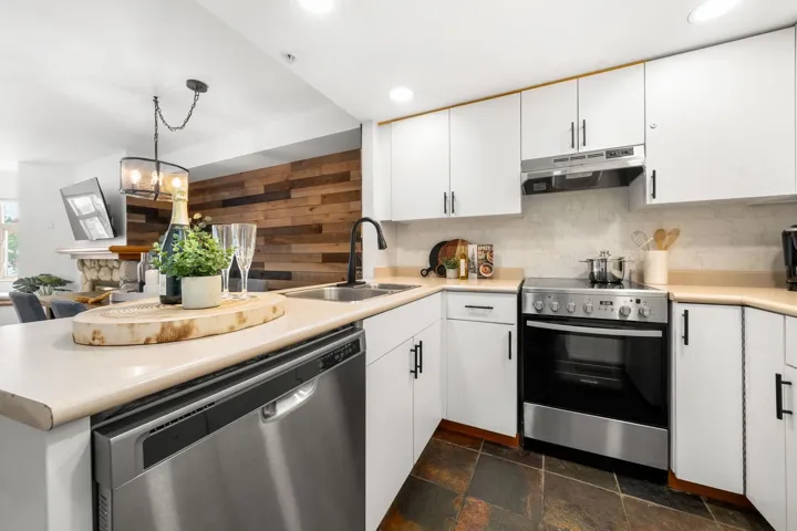 Modern kitchen featuring white cabinetry, light-toned countertops, and a full suite of stainless steel appliances including a dishwasher and range
