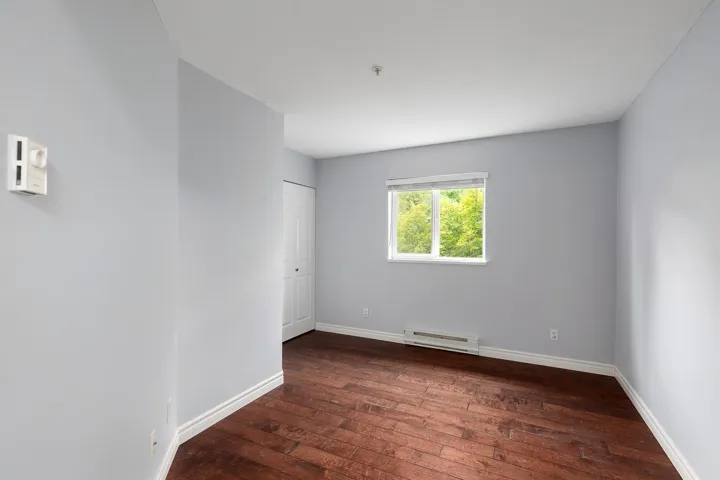 Room featuring wood-finish flooring, light gray walls, white baseboards, and a window with white trim
