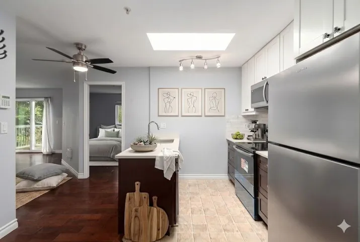Kitchen featuring an island with a breakfast bar, stainless steel appliances, white cabinetry, and a skylight