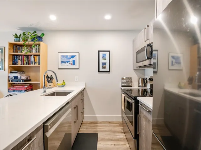 Kitchen featuring light countertops, light wood-style flooring, modern cabinets, stainless steel appliances, and a sink