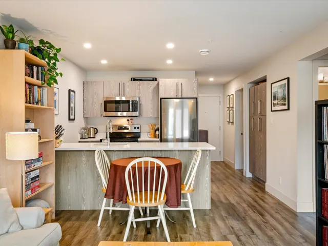Kitchen featuring light countertops, a sink, wood finished floors, appliances with stainless steel finishes, and a peninsula