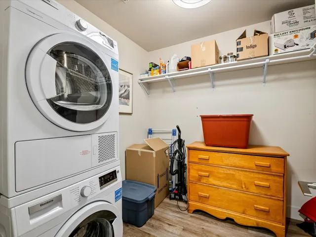 Laundry room featuring light wood-style floors, stacked washer / drying machine, and laundry area