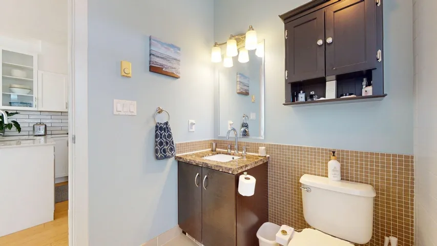 Bathroom with vanity, tile walls, a wainscoted wall, tasteful backsplash, and wood finished floors